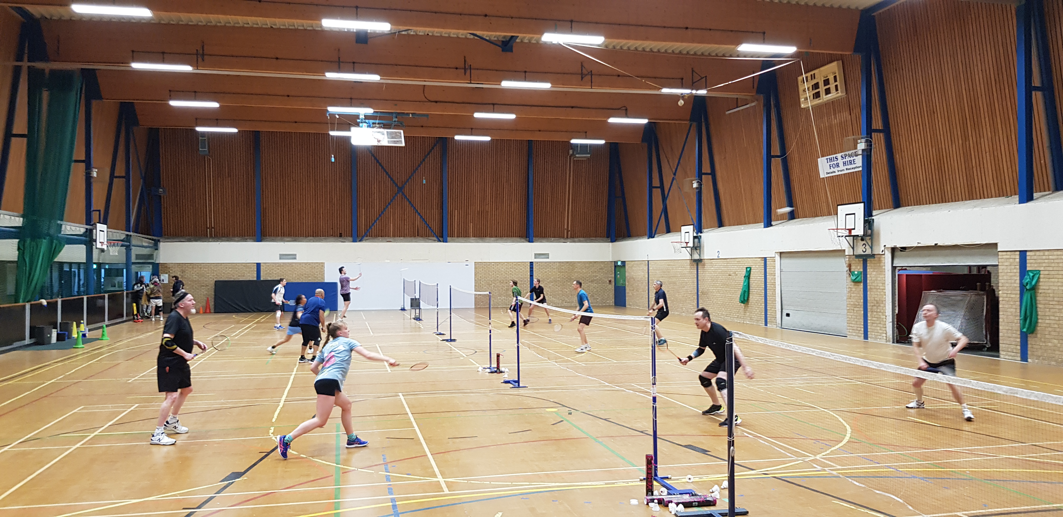 Broad demographic of badminton players. 16 players on 4 courts playing
